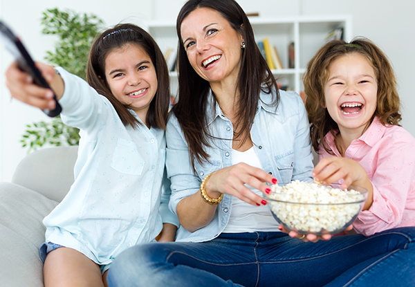 Portrait of beautiful mother and her daughters eating popcorns at home.